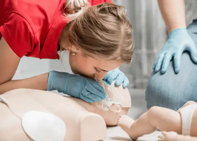 A woman demonstrates how to give a proper CPR rescue breath on a manakin as part of DRSABCD.
