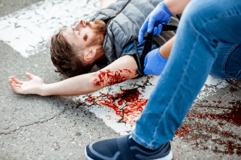 A torniquet is applied to a man who is bleeding out as a first aid triage priority.