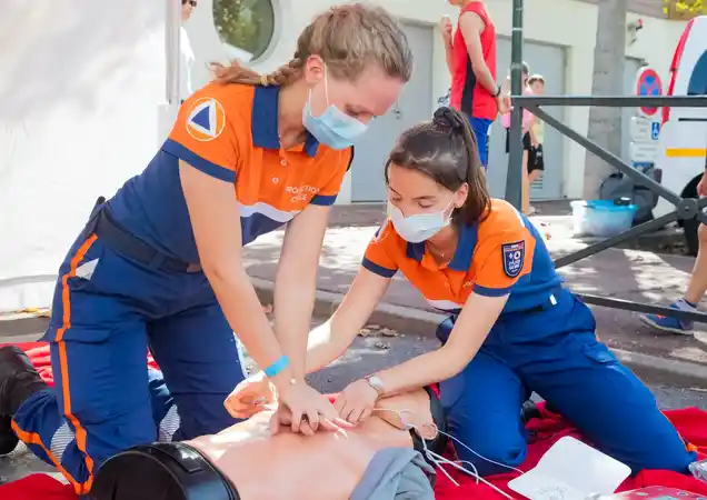 two women follow their first aid duty of care in the workplace giving cpr to an injured man(ikin)