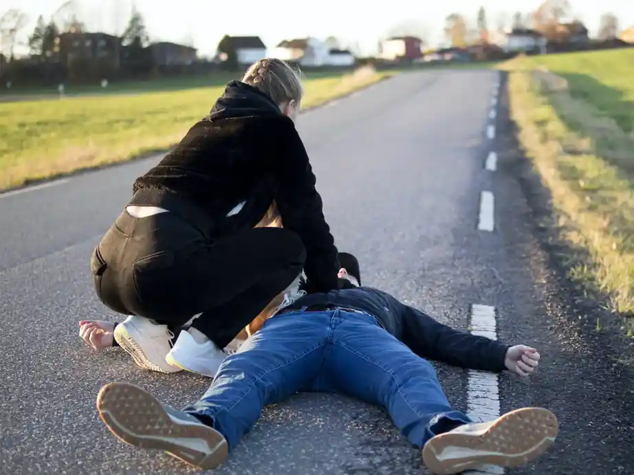a woman is stopped on a road giving cpr