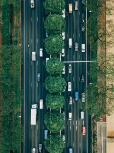 Multiple cars are on an 8 lane highway with nature strips