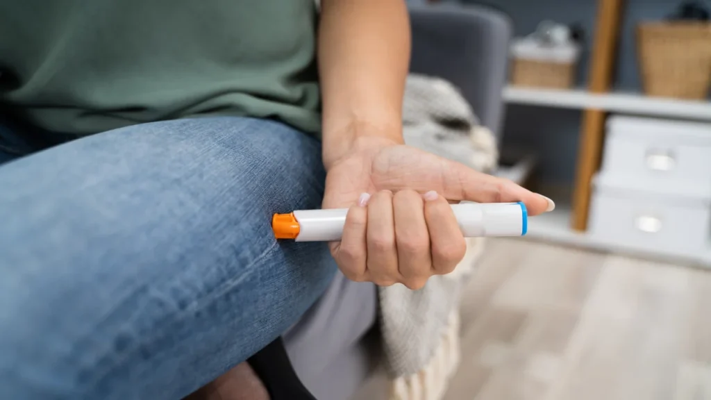 a person injects an epi pen into their thigh