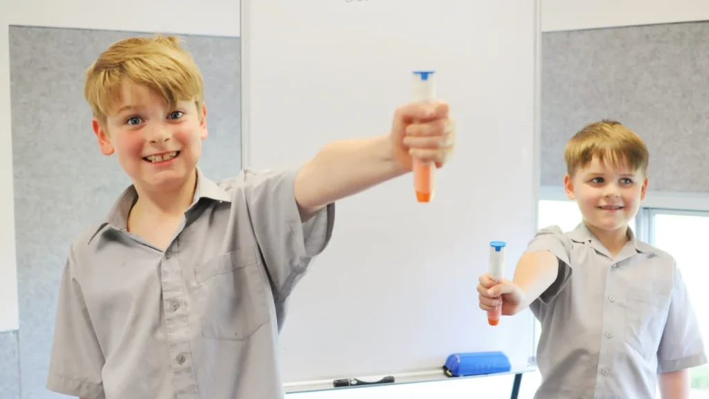 two school aged children hold up epi pens happily