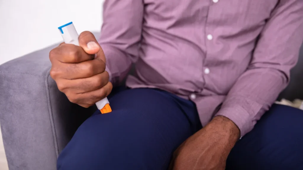 a man uses an epi pen and presses it against his thigh