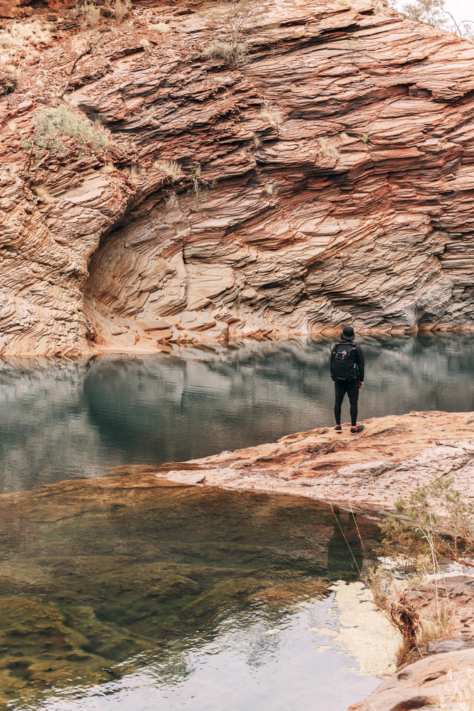 Hiker stands admiring remote waterhole
